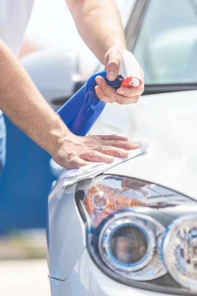 Primer plano de hombre de limpieza de la campana del coche y faros con paño y botella de pulverización, concepto de mantenimiento del coche. Espacio para copia . — Foto de Stock