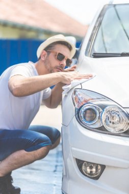 Arabasını mikrofiber bezle parlatan adamın yakın çekim.