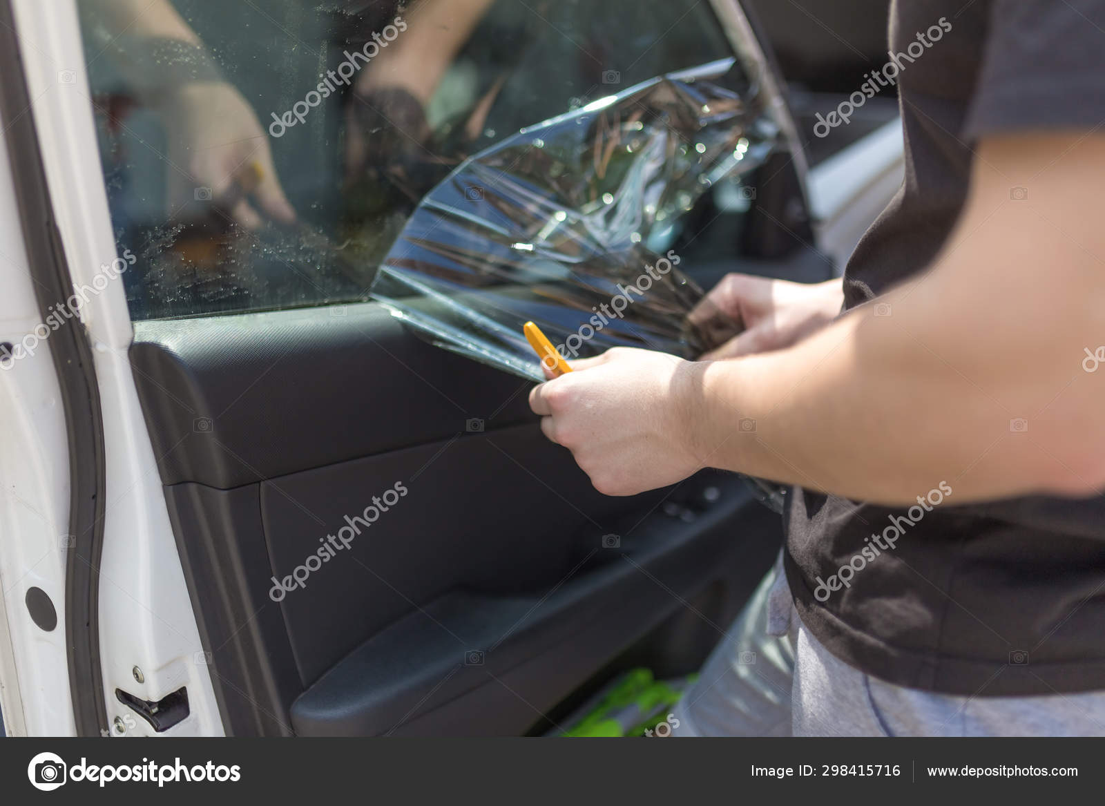 Tinted dark glass foil removal from car window. Stock Photo by