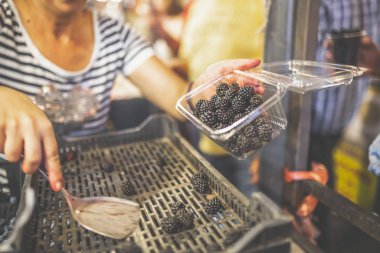 Plastik kapta porsiyon yaparak böğürtlen satan satıcı.