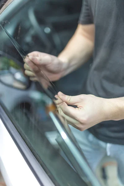 Крупним планом руки чоловіка прибирання старого автомобіля віконної плівки тону . — стокове фото