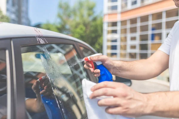 Man hands cleaning and spaying car exterior. Shit bird dropping on car window. — Stock Photo, Image