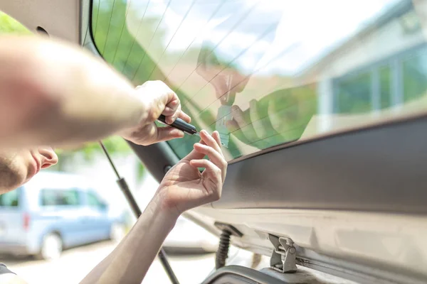 Travailleur enlever le vieux verre de fenêtre de voiture feuille de teinte protectrice de la fenêtre du coffre . — Photo