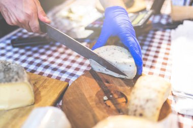 Sokak pazarı gıda festivalinde tahta tahta üzerinde bıçaklı peynir kesen adam.