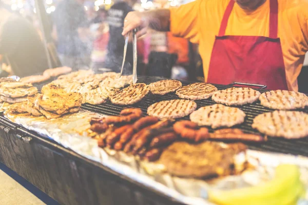 Homme préparant des hamburgers et des saucisses au festival de rue . — Photo