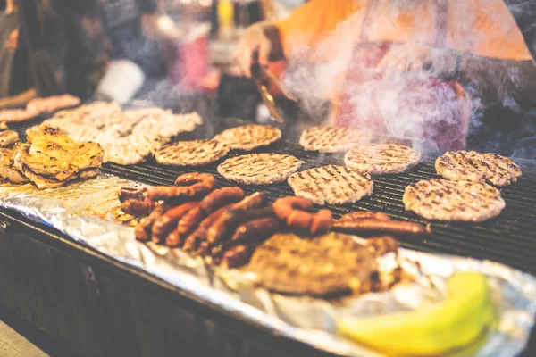 Chef préparant hamburgers et saucisses au festival de rue . — Photo