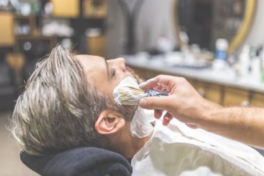 Berber dükkanında sakal tıraşı sırasında moda adam müşteri.