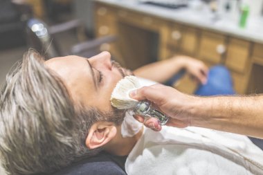 Berber dükkanında sakal tıraşı sırasında moda adam müşteri.