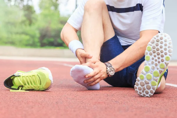 Ayak bileği ya da ayağı kırılmış ya da burkulmuş gibi hisseden koşucu. Sabah egzersizi sırasında koşu pistinde kaza. Spor kazası ve ayak burkulması kavramları.