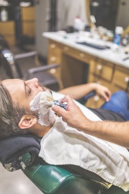 Berber dükkanında sakal tıraşı sırasında moda adam müşteri.