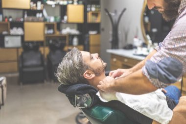 Berber ona berber dükkanında bir tıraş vermeden önce havlu ile müşteri kapsayan.