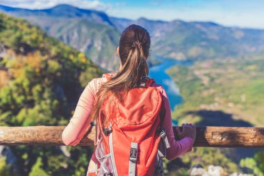 Dişi bir sırt çantası dağın tepesinde vadi manzarasının keyfini çıkarıyor. Yürüyüş ve sağlıklı yaşam tarzı konsepti.