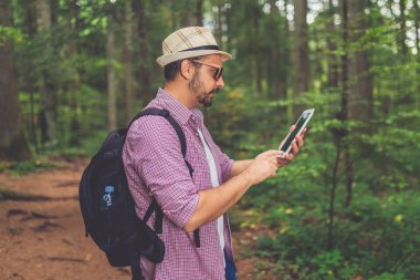 Ormanda dijital tablet kullanan modaya uygun bir turist..