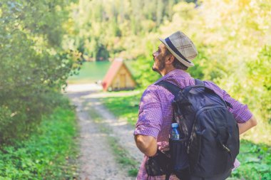 Doğadaki genç gezgin, göl ya da nehre ve küçük dağ evine karşı. Rahatlama ve sağlıklı yaşam tarzı konsepti.
