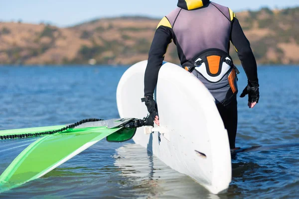 Részlet a szél szörfös holding board és vitorla, miközben készül az útra. — Stock Fotó