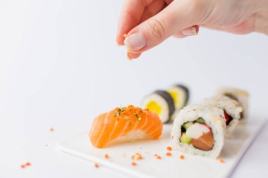 Beyaz arka planda izole edilmiş suşi tabağında somon nigiri soslu kadın eli. Japon yemek hazırlama konsepti.