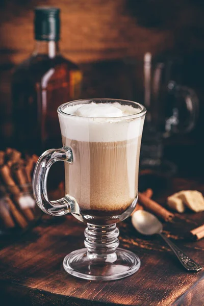 Coffee with Irish whiskey and whipped cream in glass on rustic wooden surface