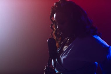 Sahnede bir caz şarkıcısı sahne alıyor. Afro.