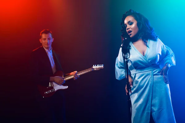 Sahnede bir caz şarkıcısı sahne alıyor. Afro.