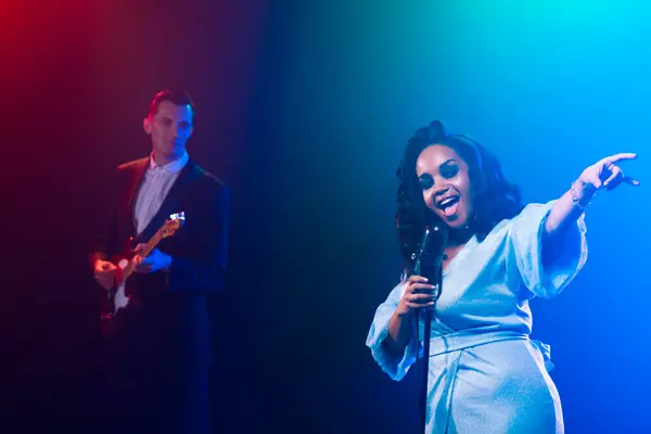 Sahnede bir caz şarkıcısı sahne alıyor. Afro.