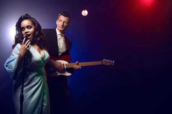 Sahnede bir caz şarkıcısı sahne alıyor. Afro.