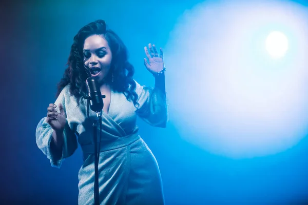 A jazz singer performs on stage. Afro.