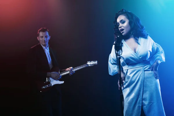 Sahnede bir caz şarkıcısı sahne alıyor. Afro.