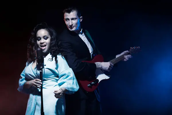 Sahnede bir caz şarkıcısı sahne alıyor. Afro.