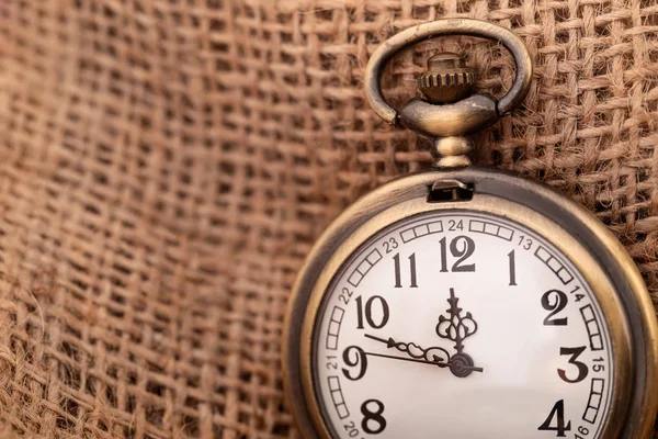 Старий кишеньковий годинник на тлі мішковини — стокове фото