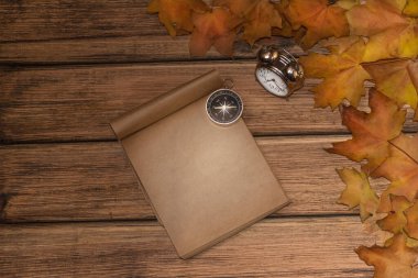 Eski ahşap arka planda sonbahar yaprakları, yakın planda bir plaka var.