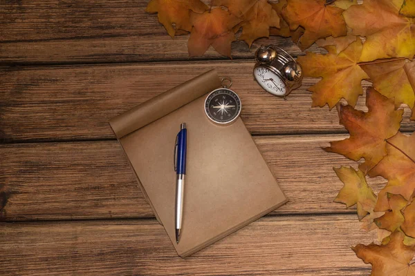 Eski ahşap arka planda sonbahar yaprakları, yakın planda bir plaka var.