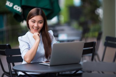 Kafede dizüstü bilgisayar kullanan mutlu kadın