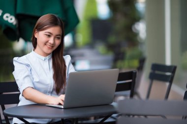 Kafede dizüstü bilgisayar kullanan mutlu kadın