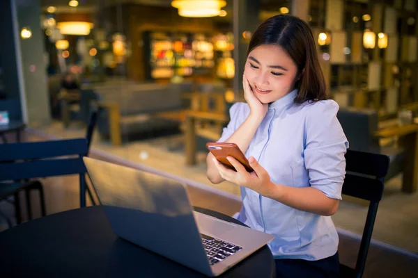 Glückliche Frau nutzt Smartphone in der Nacht im Café — Stockfoto