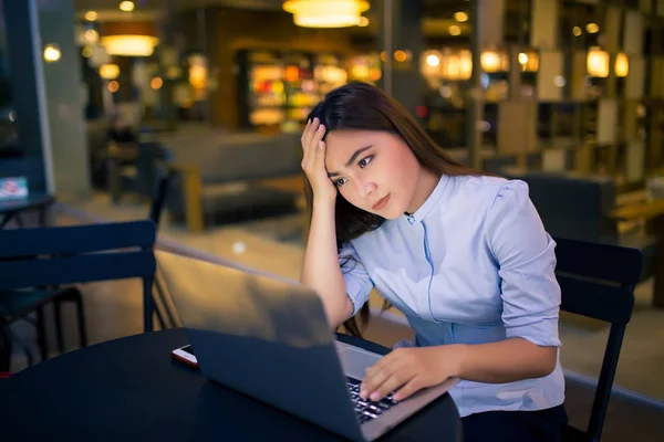 Жінка використовує ноутбук в нічний час в кафе вона почувається стурбованою — стокове фото