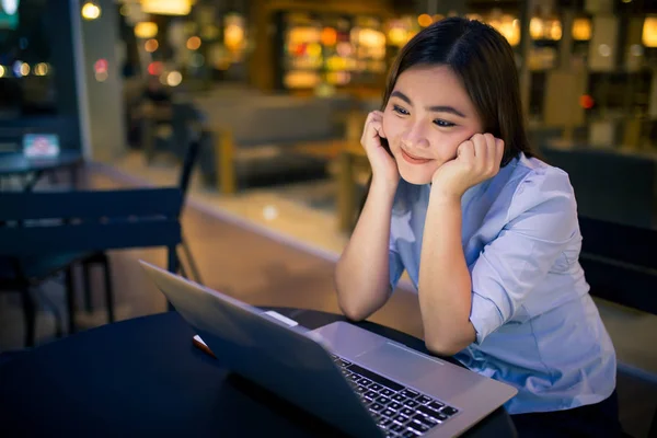 Застенчивая женщина использует ноутбук в ночное время в кафе — стоковое фото