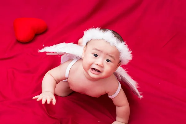 Triste bebê cupido no fundo vermelho — Fotografia de Stock