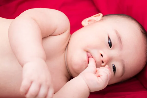 Glad asiatisk baby på röd bakgrund — Stockfoto