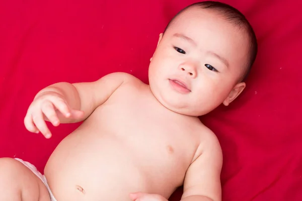 Feliz asiático bebê no fundo vermelho — Fotografia de Stock