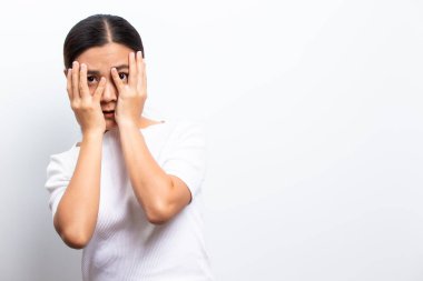 Beyaz arka planda yalnız duran korkmuş kadın.