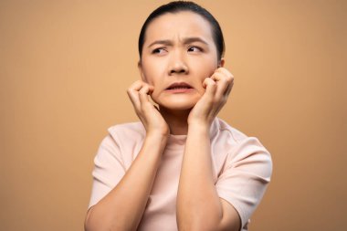 Asyalı kadın hastaydı, derisi kaşınıyordu, derisini kaşıyordu, bej arka planda tek başına duruyordu..