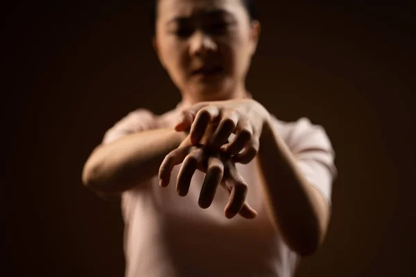 Asyalı kadın cildini kaşındıran, cildini kaşıyan, bej arka planda tek başına duran hasta bir kadındı..
