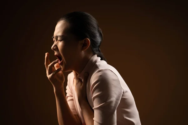 アジア系の女性は喉が痛く 咳をしてくしゃみをし ベージュ色の背景に孤立して立っていた 鍵が低い — ストック写真
