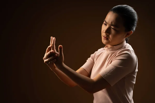 Asian woman was sick with body pain touching her body and standing isolated on beige background. Low key.