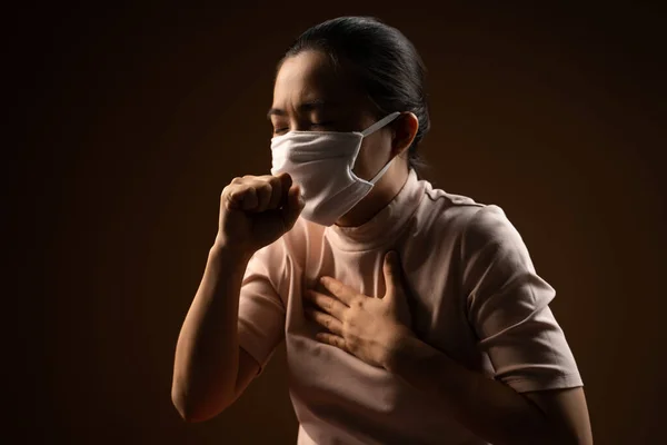 ウイルスや病気から保護するための保護マスクを身に着けているアジアの女性はベージュの背景に隔離された立って咳 鍵が低い — ストック写真
