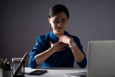 Mavi gömlekli Asyalı kadın ateşler içinde hastaydı. Ofiste dizüstü bilgisayarla çalışıyordu. Beyaz arka planda izole edilmiş. Alçak tuş.