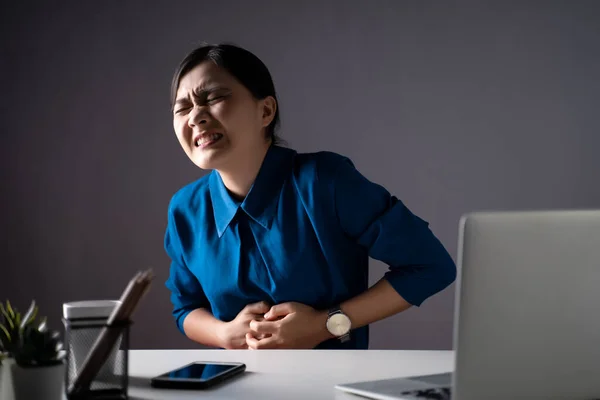 Mavi Tişörtlü Asyalı Bir Kadın Laptopta Çalışırken Mide Ağrısı Çekiyordu — Stok fotoğraf