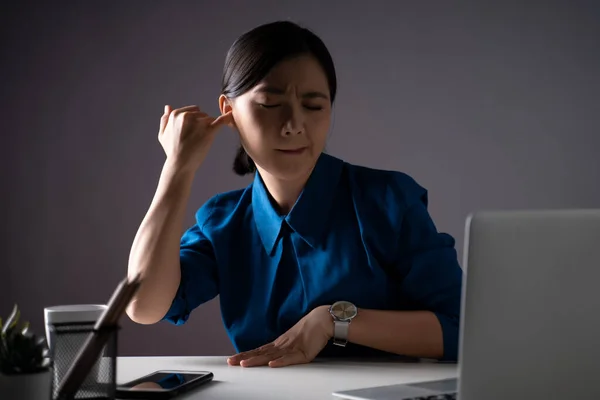 Mavi Gömlekli Asyalı Kadın Kaşınıyor Kulağına Parmağını Sokuyor Ofiste Dizüstü — Stok fotoğraf