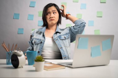 Asyalı bir kadın laptopta çalışırken kafasını kaşıyarak evde otururken kafası karışıyor. Dünya Sağlık Örgütü. Evden çalışıyorum. Coronavirus COVID-19 önleme kavramı.