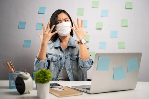 Don\'t Touch Your Face. Asian woman wearing protective face mask showing hand making stop sign at home office. WFH. Work from home. Prevention Coronavirus COVID-19 concept.